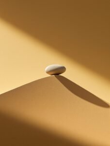 Affiche dramatique pierre poli en équilibre sur crête de sable éclairage cinématographique ombres longues