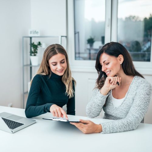 Deux femmes entrepreneures examinant un document ensemble, symbolisant une collaboration stratégique et réussie.